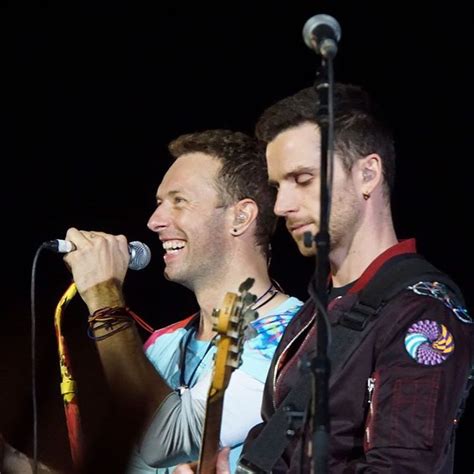 Two Men Standing Next To Each Other With Microphones In Their Hands And