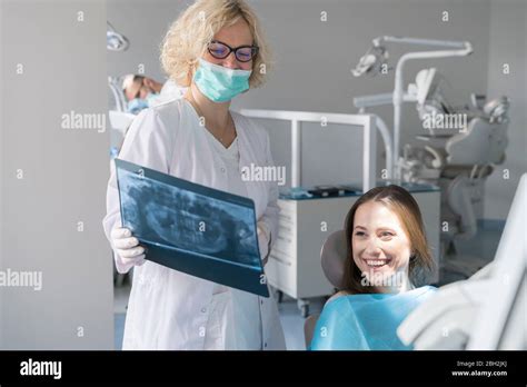 Young Woman Getting Dental Treatment In Clinic Doctor Explaining X Ray