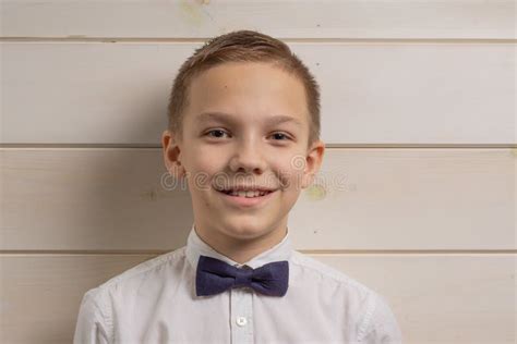A Boy Of 10 Years Old Is Smiling On The Background Of A Wooden Wall