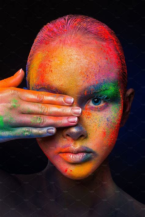 A Woman S Face Is Covered In Multicolored Paint And Has Her Hands On Her Head