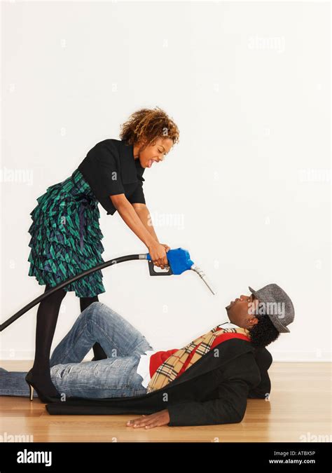 Man On Floor With Angry Woman Standing Over Him Pointing Gasoline Pump