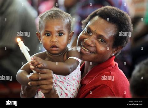 Mother With Young Girl Holding Candle In A Church In Kiunga Papua New