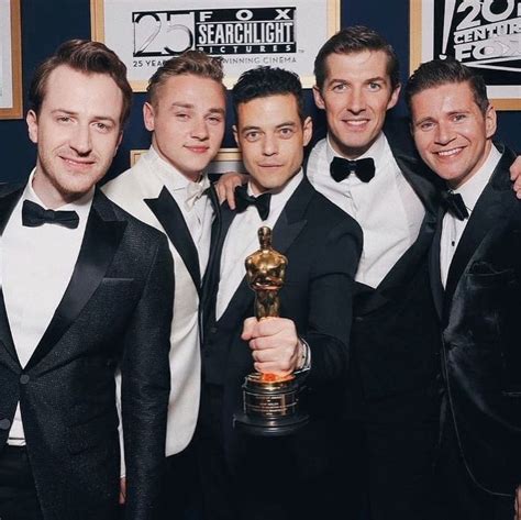 Three Men In Tuxedos Pose With An Award For Best Performance At The Oscars