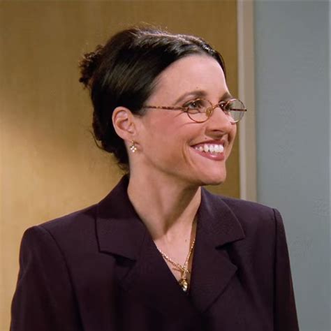 A Woman With Glasses Smiling And Wearing A Purple Suit On The Set Of