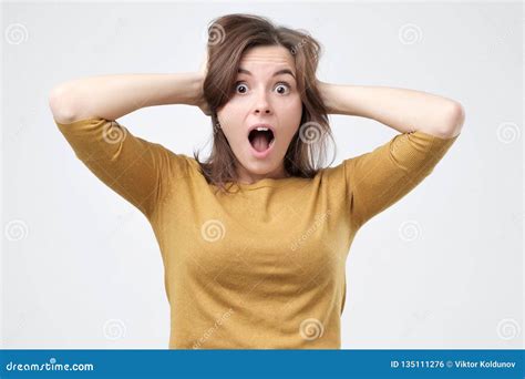 Shocked Amazed Young Woman With Hands On Head Standing And Shouting