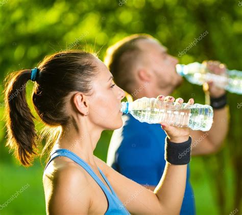 Man And Woman Drinking Water From Bottle After Fitness