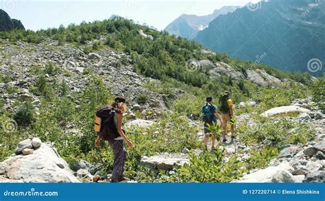 Group Tourists Hikers Walking With A Backpack In The Bushes In The