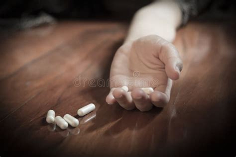 Drug Abuse Concept Passive Hand On Floor With Spilled Pills Stock