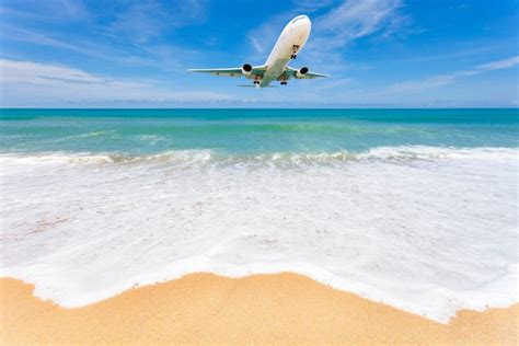 Airplane Landing Above Beautiful Beach And Sea Background Stock Photo