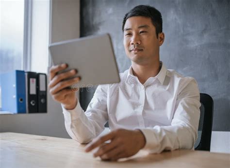 Young Asian Businessman Working On A Tablet In An Office Stock Image