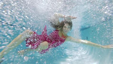 Underwater View Of Woman Wearing Dress Falling Into Swimming Pool