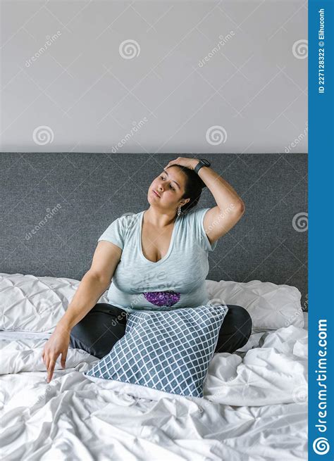Latin Girl Plus Size Relaxing Neck Sitting On Bed In Latin America Plus Size Woman Stock Photo