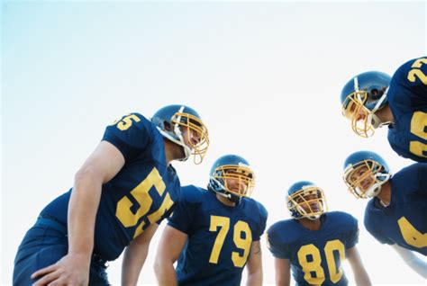 Huddle Of Pro American Football Team Against Clear Sky Stock Photo