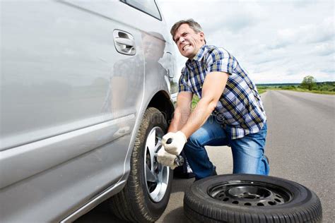 Man Changing New Spare Wheel After Vehicle Hit Rock On Countryside Sand Road Stock Image