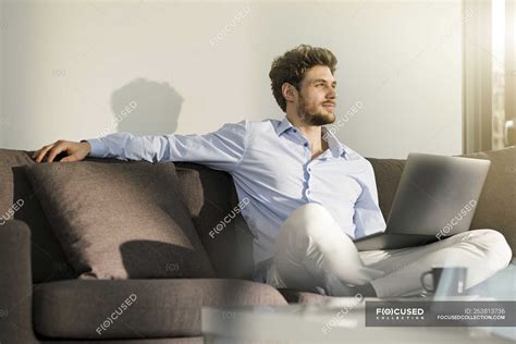 Hombre Sentado En El Sofá En Casa Con El Ordenador Portátil