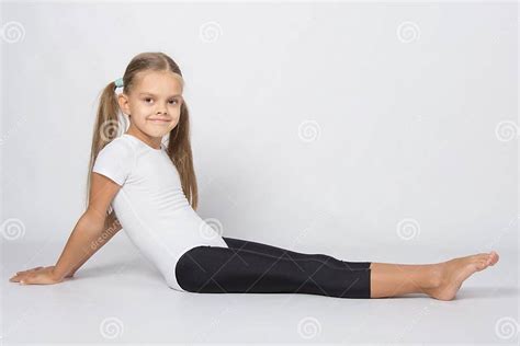 Girl Gymnast Sitting On The Floor With Legs Stretched And Leaned Back