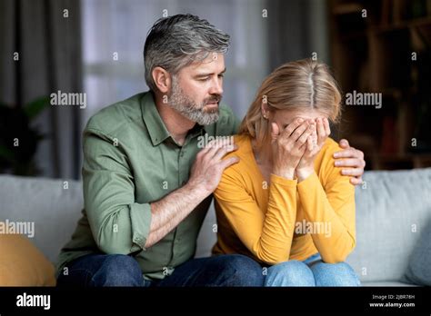 Caring Middle Aged Man Comforting His Depressed Crying Wife At Home