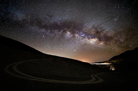 Night Sky With Wilky Way And Stars Over Curvy Dirt Road From Urban City