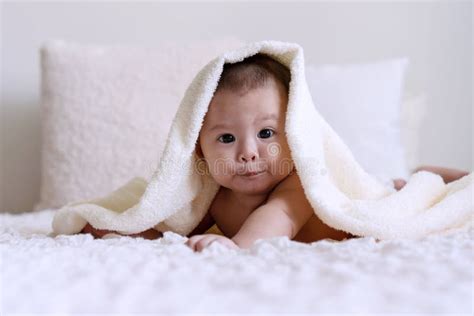 Cute Baby Looking At Camera Under White Blanket Looking At Something