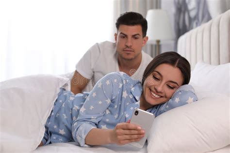 Distrustful Man Peering Into Girlfriend`s Smartphone Jealousy In Relationship Stock Image