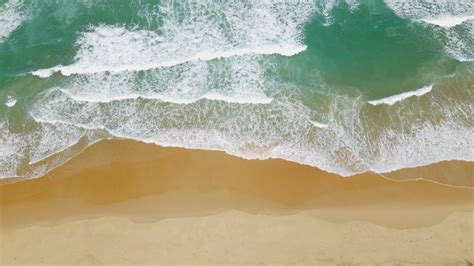 Aerial View Of Sand Beach And Water Surface Texture Foamy Waves With