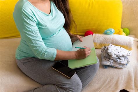 Cute Pregnant Woman Writing Packing List For Maternity Hospital With