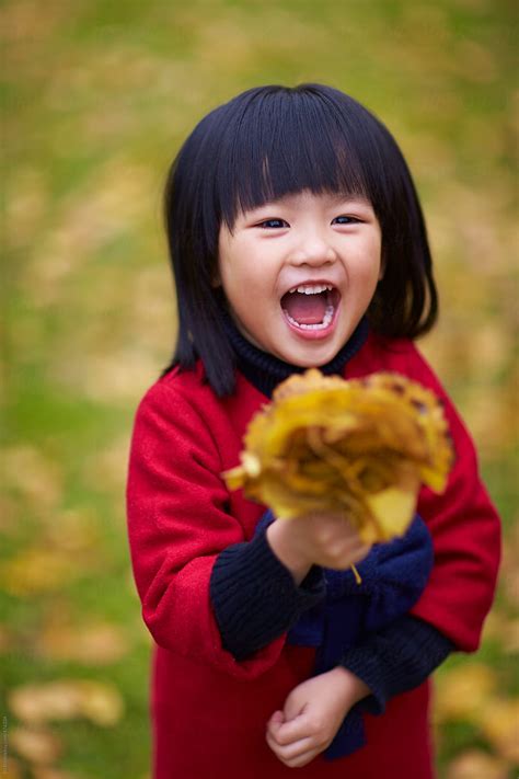 happy-little-asian-girl-holding-gingko-leaf-smile-by-bo-bo-stocksy-united