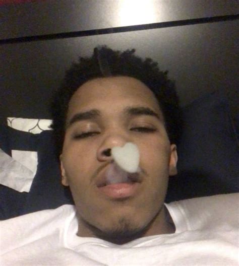 a man laying in bed with his nose open and an object sticking out of his mouth