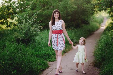 Mom Keeps Daughter S Hand And Walks The Walk On The Nature In Sunset