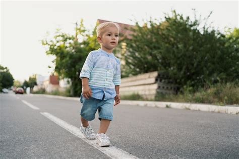 Retrato Do Menino Bonitinho Andando Na Estrada Em Seu Bairro Foto Grátis