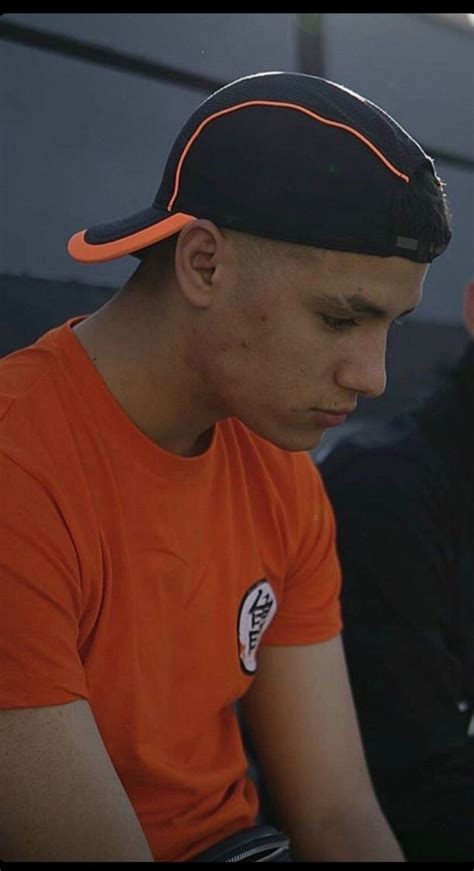 Two Men Sitting Next To Each Other Wearing Orange Shirts And Black Caps