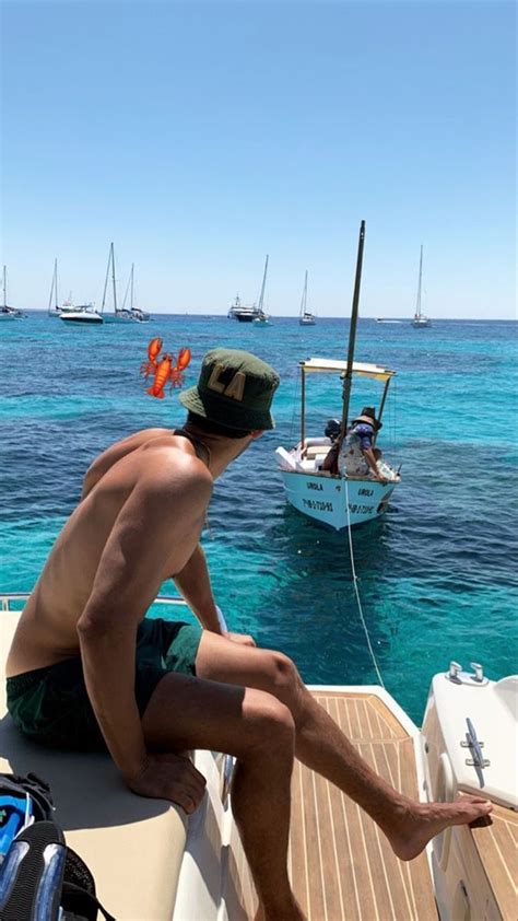 A Man Sitting On The Back Of A Boat Looking Out Over The Water With