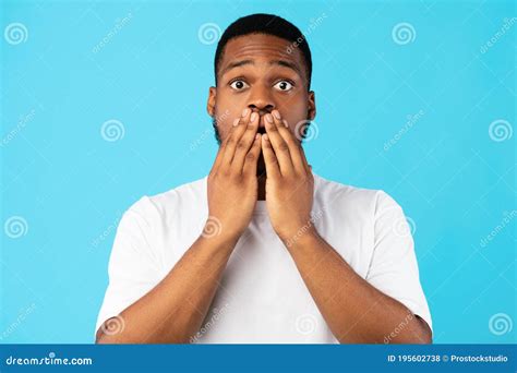 Shocked Black Guy Covering Mouth Looking At Camera Blue Background