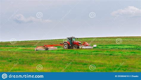 A Red Tractor Mows The Grass On A Farmer S Field Two Mowers Will Mow A