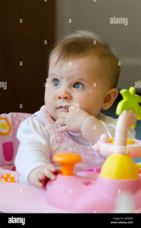 Eight Month Old Baby Girl Sitting In High Chair With Toys Stock Photo Alamy