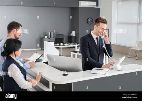 Male Receptionist Talking On Phone In Office Stock Photo Alamy