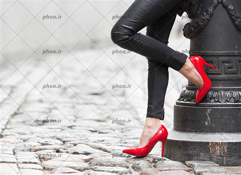 عکس با کیفیت زنی با شلوار مشکی و کفش پاشنه بلند قرمز در پیاده رو عکس با کیفیت و تصاویر استوک