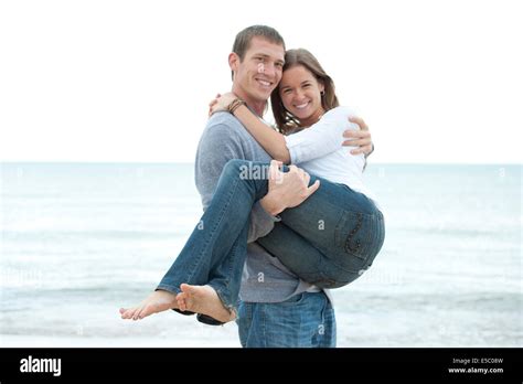A Young Man Carrying His Wife Smiling On The Beach Stock Photo Alamy