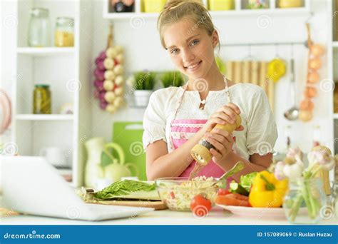 Portrait Of Young Beautiful Girl In Kitchen With Laptop Stock Image