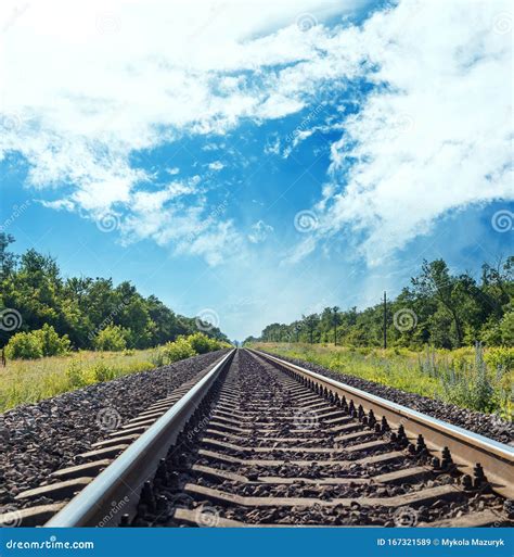 Railroad To Horizon In Green Meadow And Blue Sky With Clouds Stock