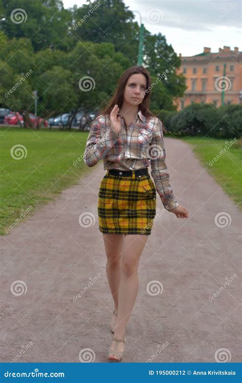 Slender Brunette Girl In A Plaid Skirt In The Summer In The Park Stock