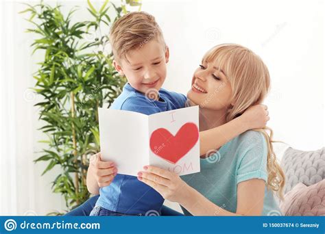 Portrait Of Cute Little Boy And His Mother With Handmade Card At Home