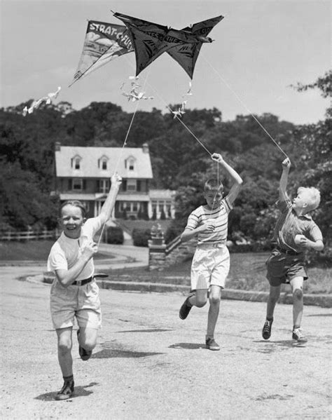 Black And White Photograph Of Three People Running With A Kite In The
