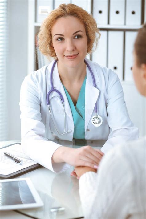 Happy Blonde Female Doctor Looking At Patient While Speaking To Her And