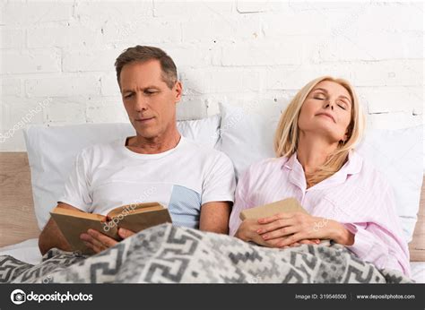 Man Reading Book Wife Sleeping Bed — Stock Photo © Igorvetushko 319546506