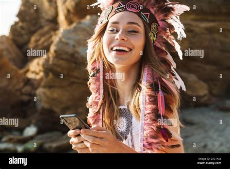 Image Of Happy Hippy Girl In Feather Indian Headdress Holding Cellphone