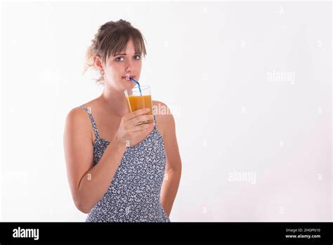 A Young Adult Woman Drinking A Fruit Juice With A Straw On A White