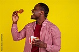 funny african american man eating fried chicken leg in studio yellow ...