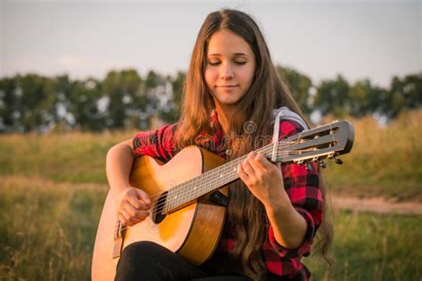 Young Girl Playing The Guitar On Meadow Stock Photo