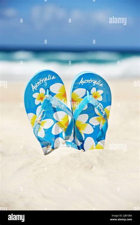 A Pair Of Thongs Standing Upright In The Sand At The Beach Stock Photo